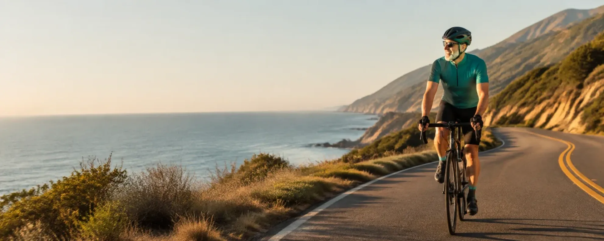 Cyclist riding a coastal road at golden hour